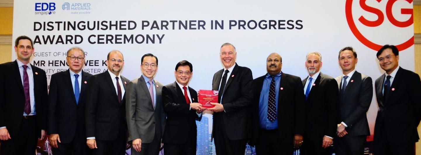 Group of people at EDB and Applied Materials award ceremony, holding a red award.